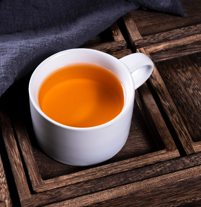 Hot rooibos tea in a white mug on a wooden tray