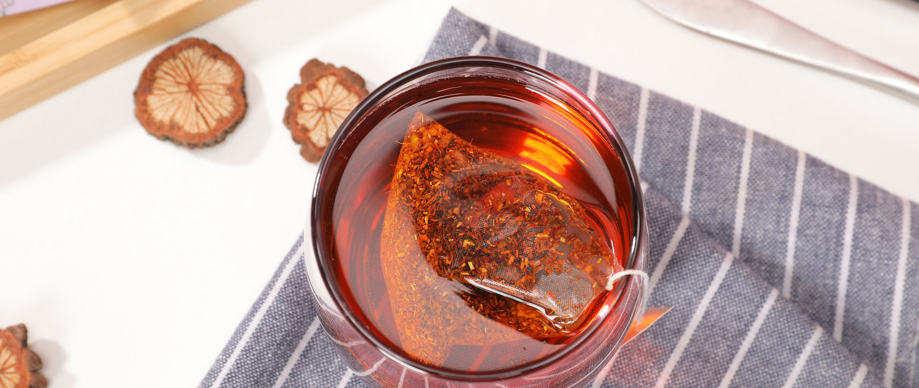 Rooibos tea bag brewing in a glass cup